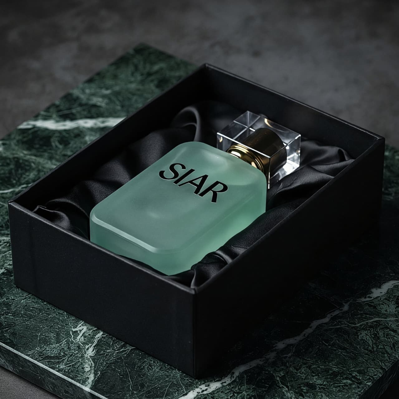 SIAR Bloom perfume bottle lying inside its box, showcasing the elegant glass design and floral-themed packaging.